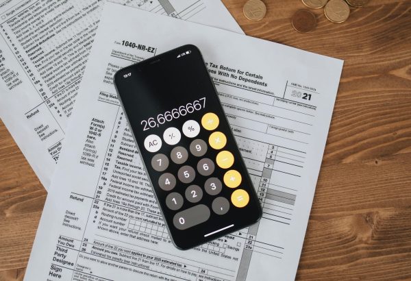 Overhead view of smartphone calculator on tax forms for finance and accounting.